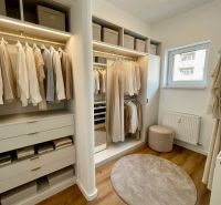 A wardrobe in a 4-room apartment with a wooden decor floor and light furniture.
