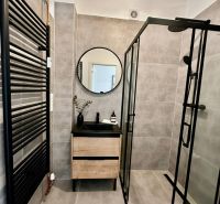 A bathroom in a 4-room apartment with a shower corner and a floor with a wooden decor.