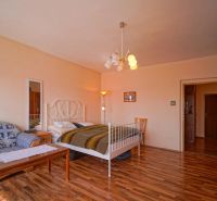 A bedroom in a family house with a bed, a sofa, and a wooden decor floor.
