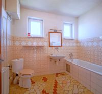 A bathroom in a family house with patterned tiles and a bathtub.