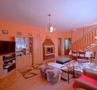 Living room in a family house with a staircase, fireplace, and wooden decor flooring.