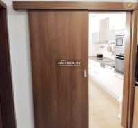 A kitchen with built-in appliances in a 2-room apartment, separated by wooden sliding doors.
