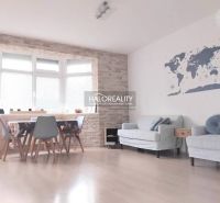 A bright living room in a two-room apartment with a wooden decor floor and a world map on the wall.