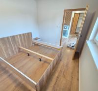 A bedroom with a bed and a wooden decor floor in a family house.