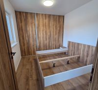 Bedroom in a family house with a bed and a wardrobe, floor with wooden decor.