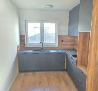 A kitchen in a family house with dark cabinets and a wood-patterned floor.
