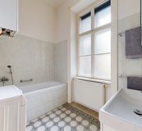 A bathroom with tiled walls and floor, a bathtub, a sink, and a washing machine in a 4-room apartment.
