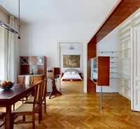 Dining room in a 4-room apartment with a wooden table, wooden decor flooring, shelves, and a bedroom.