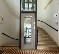 A hallway with a staircase and an elevator in a 4-room apartment with geometric patterned tiles.