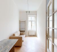 A narrow room with a sofa, a window, and a floor with a wooden decor in a 4-room apartment.
