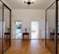 In the hallway of the 4-room apartment, there are mirrored doors and a floor with a wooden decor.