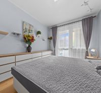 Bright bedroom in a 3-room apartment, gray bedspread, decorations, and floor with wood decor.