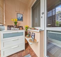 A balcony in a 3-room apartment with a chest of drawers, decorations, and a view of the apartment building.