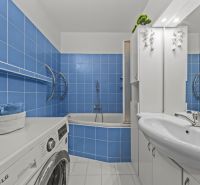A bathroom with blue tiles, a bathtub, a washing machine, a sink, and storage space in a 3-room apartment.