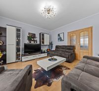 Living room in a three-room apartment with a wooden decor floor and a comfortable sofa set.