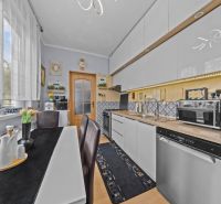 A kitchen in a 3-room apartment with a dining table, appliances, and white cabinets.