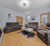 Living room with a comfortable sofa, table, and wooden decor flooring in a 3-room apartment.