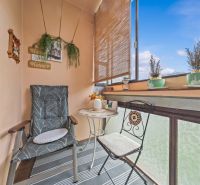A furnished balcony in a 3-room apartment with comfortable chairs, a table, and decorations.