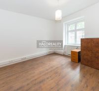 A room with a wooden floor, simple furniture, and a large window.