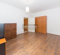 A spacious room with wooden flooring and simple furniture in a five or more room apartment.