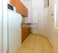 A narrow kitchen with appliances and wooden cabinets in a 5 or more room apartment.