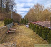 A garden with a terrace around the cottage in Kvakovce, surrounded by trees and shrubs.