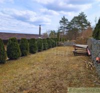 A garden at the cottage in Kvakovce with conifers and stone walls.