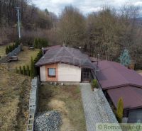 A cottage in Kvakovce surrounded by greenery near the forest with a manicured lawn and a road.