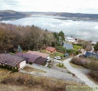 View of the lake in Kvakovce with cottages and green trees in the surroundings.