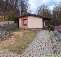 A cottage in Kvakovce surrounded by nature with a paved walkway and surrounding trees.