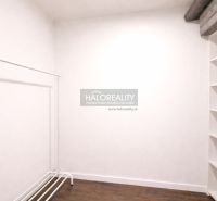 A white room with a clothes rack and shelves, floor with wood decor.