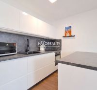 A kitchen in a 2-room apartment with a white kitchen unit and a floor with a wood decor.