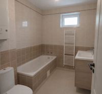 Bathroom in a 2-room apartment with a bathtub and tiles in light tones.