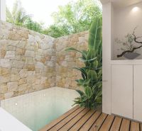 A small pool in an enclosed area of the villa with wooden floor decoration and green plants.