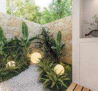 Private garden in a villa with a brick wall, plants, and spherical lamps.