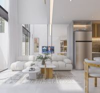 Bright living room in a villa with a sofa, television, and kitchen area with a plant.