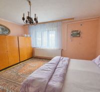 Bedroom with a bed, wardrobe, and chandelier in a family house.