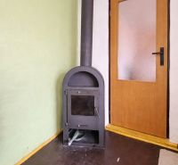Wood-burning stove near wooden doors, gray floor with floor decor.