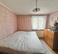 A bedroom in a family house with pink walls, a comfortable bed, and a dresser.