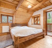 Wooden bedroom in a family house with a view, bed, wooden decor flooring, and a balcony.