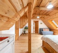 Attic in a family house with wooden wall and ceiling decor, bed, couch, furniture.