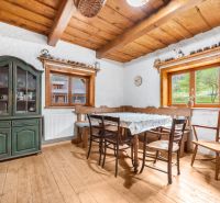 A dining room with a wooden ceiling and a floor with a wooden decor, antique furniture.