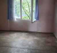 A room in a family house, an older floor, an open plastic window with blue curtains.