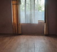 A room with a wooden floor design, curtains, and a window in a family house.