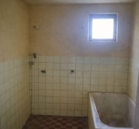 An older bathroom in a family house with a bathtub and tiled walls.