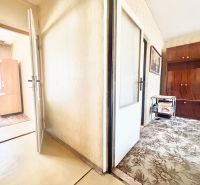 A hallway with carpet and entrance to a room in a 2-room apartment.