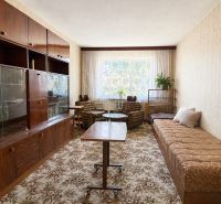 Living room in a two-room apartment with a sofa, table, and dark wood furniture.