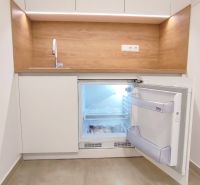 Kitchenette with a refrigerator, wooden decor flooring, and white cabinets in offices.