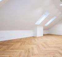 Attic space with a wooden decor floor and lighting suitable for offices.