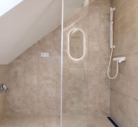 Shower enclosure with a glass wall and a showerhead on a tiled wall.